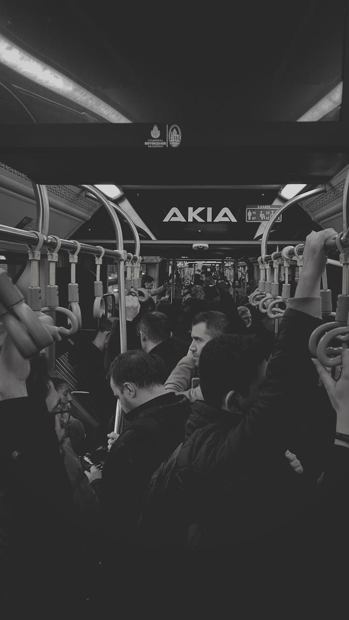 Black and white photo of a crowded bus interior with standing passengers.