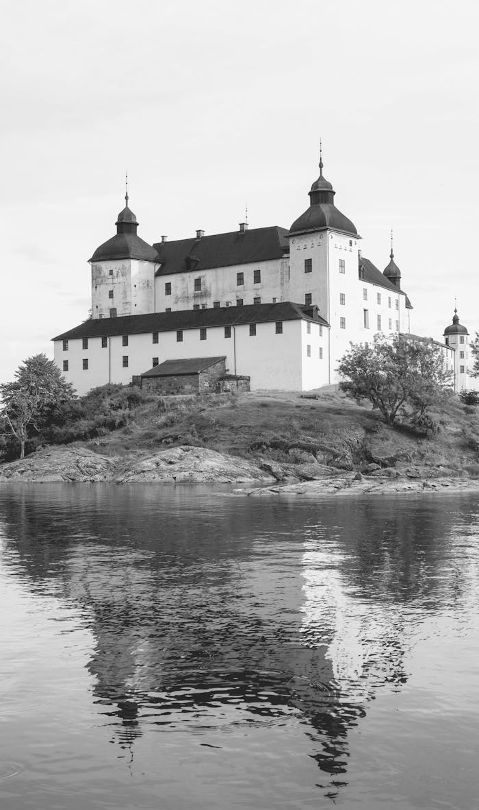 Black and white photo of LÃ¤ckÃ¶ Castle with serene reflection on Lake VÃ¤nern in Sweden.